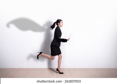 Superhero Business Woman Running And Hold Laptop Computer With White Wall Background, Great For Your Design Or Text, Asian