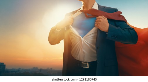 супергерой бизнесмен смотрит на горизонт города на закате. Концепция успеха, лидерства и победы в бизнесе.