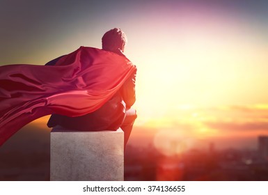 superhero businessman looking at city skyline at sunset. the concept of success, leadership and victory in business.