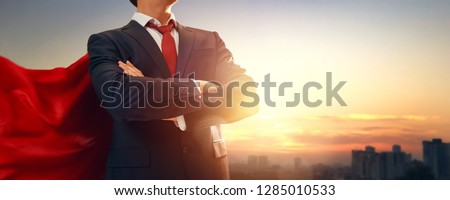 superhero businessman looking at city skyline at sunset. the concept of success, leadership and victory in business.