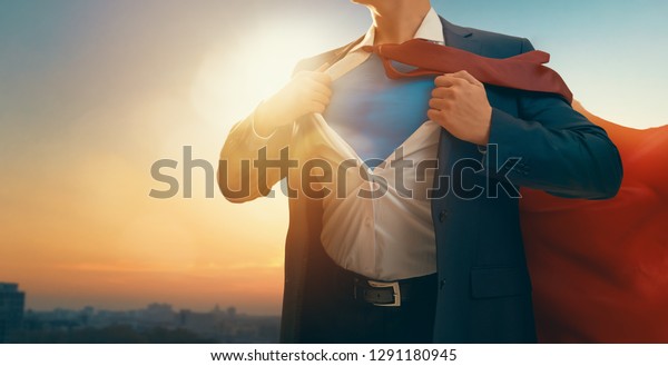 superhero\
businessman looking at city skyline at sunset. the concept of\
success, leadership and victory in\
business.