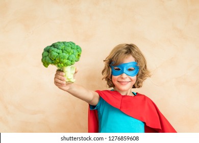 Superhero Child Eating Superfood. Happy Kid Holding Broccoli. Healthy Eating And Lifestyle Concept. Green Vegetarian Food