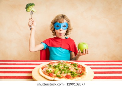 Superhero Child Eating Superfood. Happy Kid Having Lunch At Home. Healthy Eating And Lifestyle Concept. Green Vegetarian Food