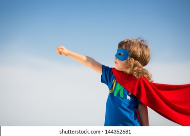 Superhero kid against blue sky background. Girl power concept