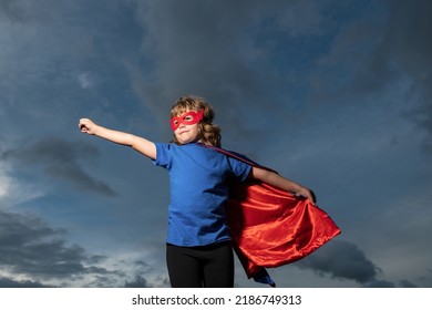 Superhero Kid Against Dramatic Blue Sky Background. Strong Super Hero Boy With Superpower.