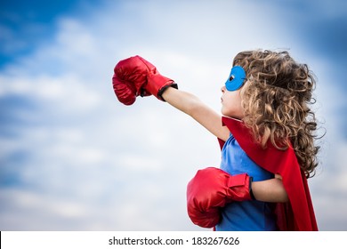 Superhero kid against summer sky background. Girl power and feminism concept - Powered by Shutterstock