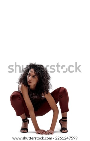 Superhero like Frontal portrait of young curly-haired woman crouched as cat-woman staring at prey in elegant dress of purple and burgundy cloths, her bare arms resting on the ground. Isolated on trans