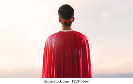 Superhero Man With Mask And Red Cape In Back Position On A Sunset Background