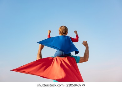 Superhero senior man and child playing outdoor. Super hero grandfather and boy having fun together against blue summer sky background. Family holiday concept. Happy Father's day. Rear view portrait - Powered by Shutterstock