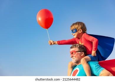 Superhero senior man and child playing outdoor. Super hero grandfather and boy having fun together against blue summer sky background. Family holiday concept. Happy Father's day - Powered by Shutterstock