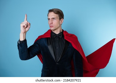 Superhero Stands In A Heroic Pose, A Man In A Business Suit And A Red Cape. Charismatic And Successful Business Hero.