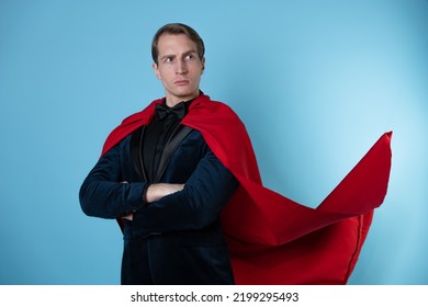 Superhero Stands In A Heroic Pose, A Man In A Business Suit And A Red Cape. Charismatic And Successful Business Hero.