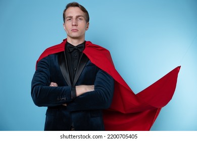 Superhero Stands In A Heroic Pose, A Man In A Business Suit And A Red Cape. Charismatic And Successful Business Hero.