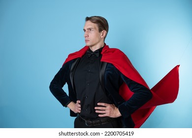 Superhero Stands In A Heroic Pose, A Man In A Business Suit And A Red Cape. Charismatic And Successful Business Hero.