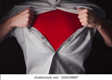 Superhero Tears off his Shirt on a dark Background. Tearing the shirt on his chest. Red t shirt hero