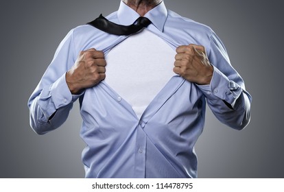 Superhero, young businessman tearing his shirt off isolated on gray background with copy space