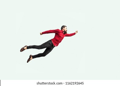 Superman Flying. Enthusiasm Concept. Strong Bearded Businessman In Red Shirt  Felt Himself A Superhero Or Super Man And Flying Up. Indoor Studio Shot Isolated On Gray Background.