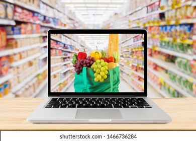 supermarket aisle blurred background with laptop computer and green shopping bag on wood table grocery online concept - Powered by Shutterstock