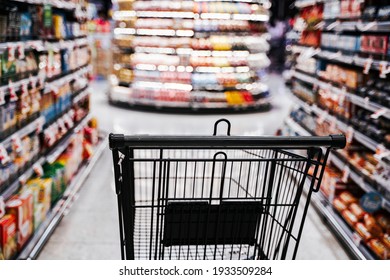 Supermarket aisle with empty black shopping cart. 