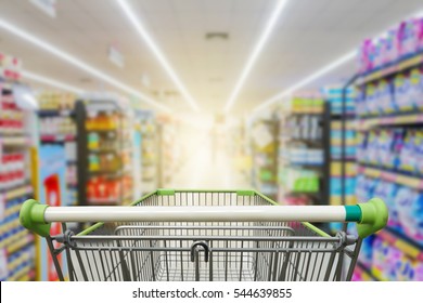 Supermarket aisle with empty green shopping cart                      