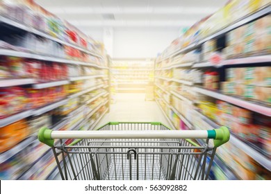 Supermarket aisle with empty green shopping cart