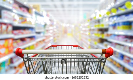 Supermarket aisle with empty red shopping cart.