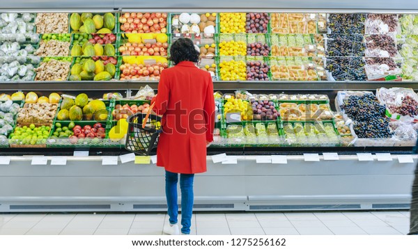 At the\
Supermarket: Alone Woman Chooses Organic Fruits in the Fresh\
Produce Section of the Store. She Picks Up Cantaloupe and Puts them\
into Her Shopping Basket. Back View\
Shot.