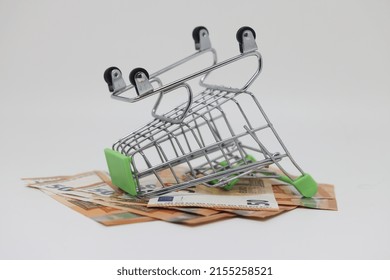 The Supermarket Basket Lies On A Pile Of Banknotes. Trolley For Shopping In A Chain Store. Lots Of Money For Shopping. The Cost Of Food And Clothing In The Store. Social Problem