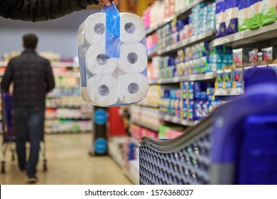 at the supermarket buying a toilet paper package, and putting it in the cart