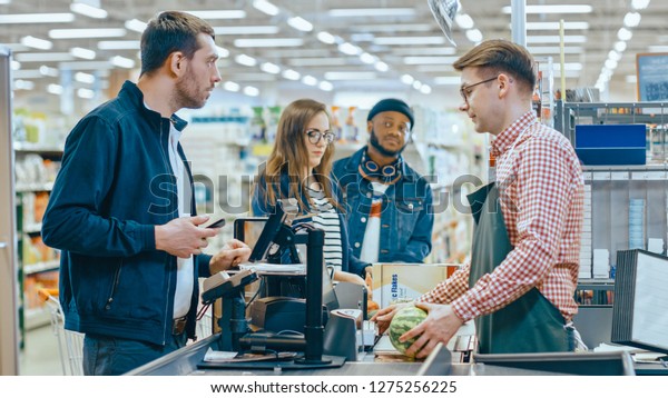 At the\
Supermarket: Checkout Counter Customer Pays with Smartphone for His\
Items. Big Shopping Mall with Friendly Cashier, Small Lines and\
Modern Wireless Paying Terminal\
System.
