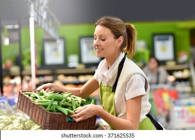 Supermarket employee putting vegetables in shelves - Powered by Shutterstock