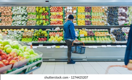 At The Supermarket: Happy Black Stylish Guy With Shopping Basket Shopping For Organic Fruits And Vegetables In The Fresh Produce Section Of The Store.