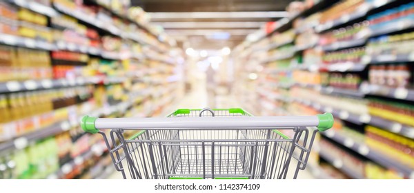supermarket shelves aisle with empty shopping cart defocused interior blur bokeh light background - Shutterstock ID 1142374109