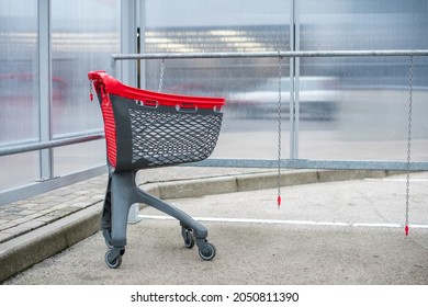 Supermarket Shopping Carts Trolley With Red Accents, Parked Outside In A Plastic Enclosure In Parking