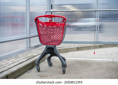 Supermarket Shopping Carts Trolley With Red Accents, Parked Outside In A Plastic Enclosure In Parking