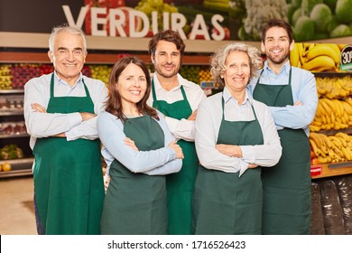 Supermarket team with happy salesmen and market leader in green aprons - Powered by Shutterstock