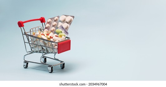 A Supermarket Trolley Full Of Blister Pills, A Lot Of Pills In A Wheelbarrow. Concept: Home Delivery Of Medicines.Empty Space, A Place For Text, Poster, Board. Medical Blue Background.