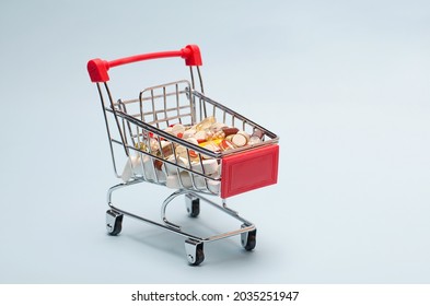 A Supermarket Trolley Full Of Blister Pills, A Lot Of Pills In A Wheelbarrow. Concept: Home Delivery Of Medicines.Empty Space, Place For Text, Poster, Board.
Medical Blue Background.