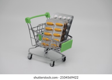 A Supermarket Trolley Full Of Blister Pills, A Lot Of Pills In A Wheelbarrow. Concept: Home Delivery Of Medicines.Empty Space, A Place For Text, Poster, Board. Medical Blue Background