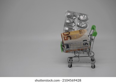 A Supermarket Trolley Full Of Blister Pills, A Lot Of Pills In A Wheelbarrow. Concept: Home Delivery Of Medicines.Empty Space, A Place For Text, Poster, Board. Medical Blue Background