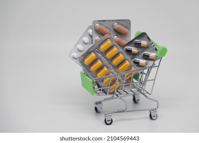 A Supermarket Trolley Full Of Blister Pills, A Lot Of Pills In A Wheelbarrow. Concept: Home Delivery Of Medicines.Empty Space, A Place For Text, Poster, Board. Medical Blue Background