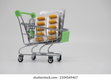 A Supermarket Trolley Full Of Blister Pills, A Lot Of Pills In A Wheelbarrow. Concept: Home Delivery Of Medicines.Empty Space, A Place For Text, Poster, Board. Medical Blue Background