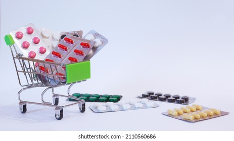 A Supermarket Trolley Full Of Blister Pills, A Lot Of Pills In A Wheelbarrow. Concept: Home Delivery Of Medicines.Empty Space, A Place For Text, Poster, Board. Medical Blue Background. 