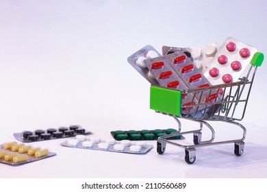 A Supermarket Trolley Full Of Blister Pills, A Lot Of Pills In A Wheelbarrow. Concept: Home Delivery Of Medicines.Empty Space, A Place For Text, Poster, Board. Medical Blue Background. 