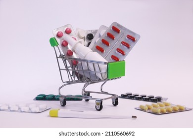 A Supermarket Trolley Full Of Blister Pills, A Lot Of Pills In A Wheelbarrow. Concept: Home Delivery Of Medicines.Empty Space, A Place For Text, Poster, Board. Medical Blue Background. 