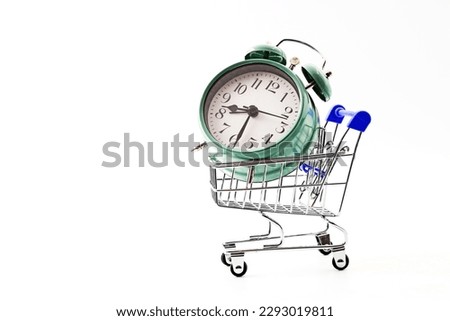 A supermarket trolley or shopping cart with an green antique or vintage alarm clock
