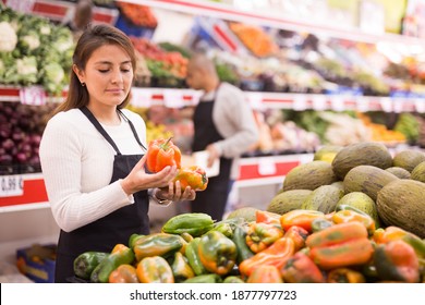 Supermarket Woman Worker In Black Apron Putting Vegetables In Her Department