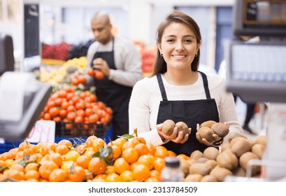 Supermarket woman worker in black apron stacking fruits - Powered by Shutterstock