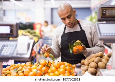 Supermarket Worker In Black Apron Stacking Fruits In His Department