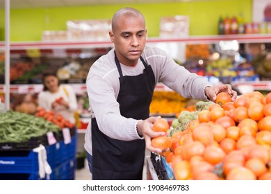 Supermarket Worker In Black Apron Stacking Fruits In His Department